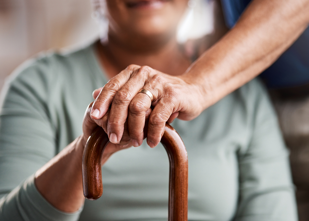 Close-up picture of hands of elderly married couple holding cane