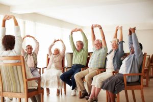 Care provider guiding group of senior clients through some exercises