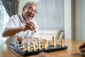 Senior man playing game of chess in room at care facility