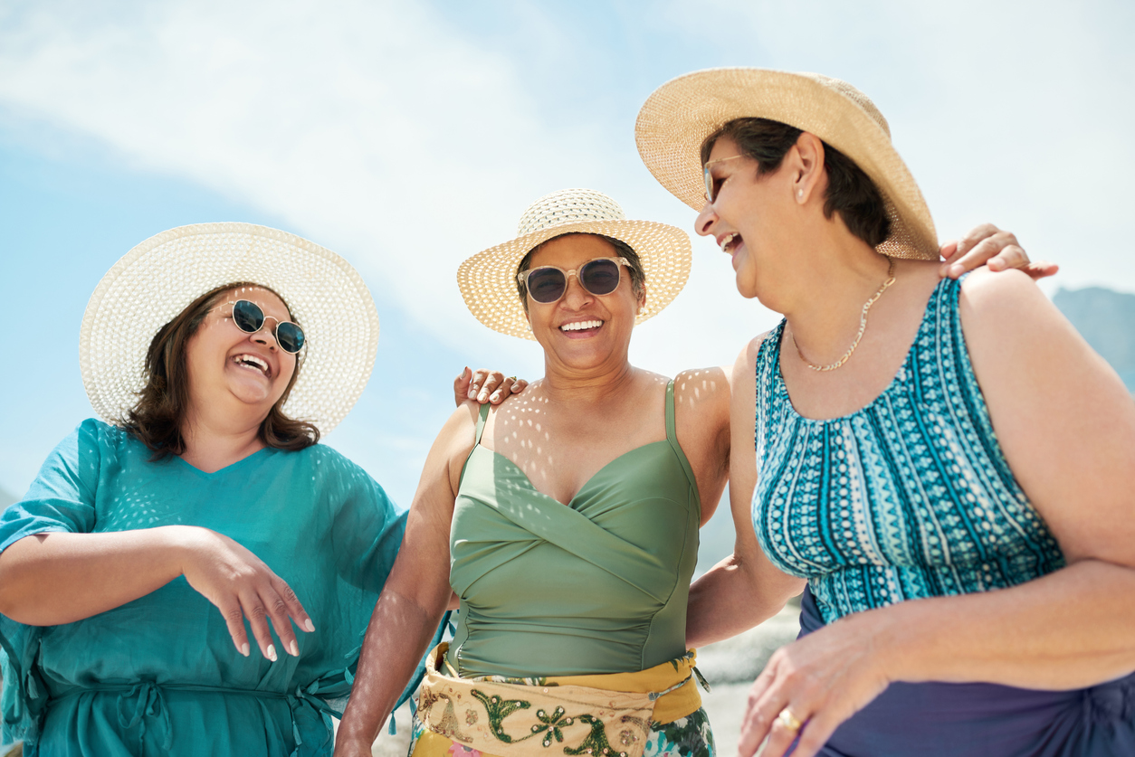 Three smiling clients in bathing suits and hats enjoy some summer sunshine