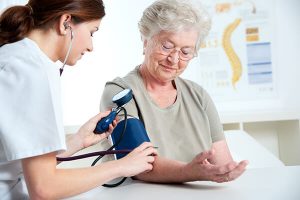 Care provider taking blood pressure of elderly client